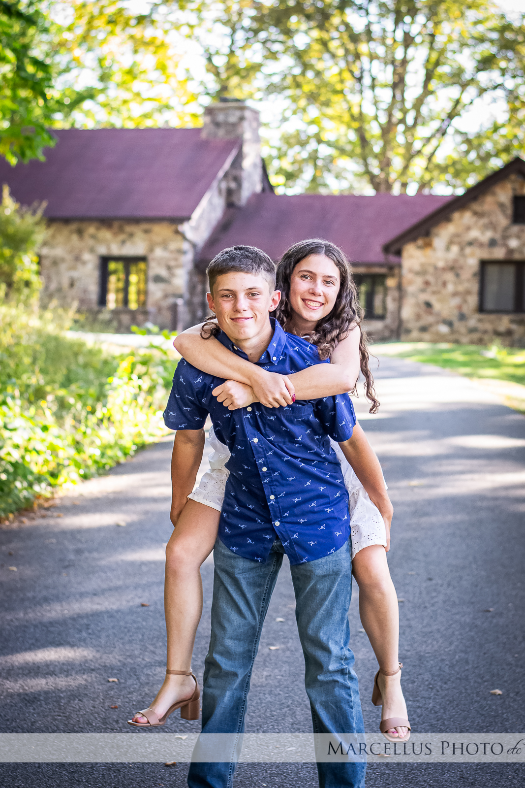 Twin siblings goofing around, sister on brothers back.