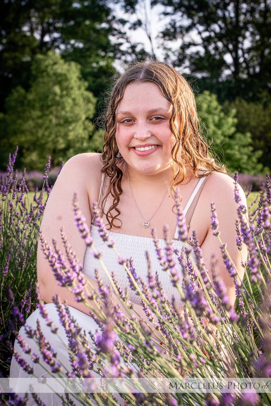 Girl in white dress kneeling in lavender field